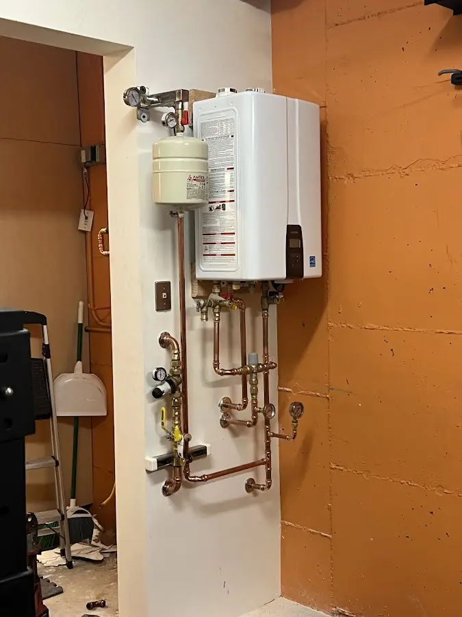 Plumbing technician inspecting water heater connections in Sleepy Eye